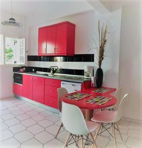 阿查拉维Philippos Apartments的厨房配有红色橱柜和红色的桌椅