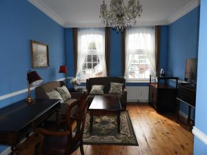 施内沃丁根Hotel Villa Schneverdingen的客厅拥有蓝色的墙壁和桌椅