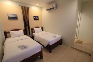 Nang Rongโรงแรมนางรอง的酒店客房,配有两张带白色床单的床
