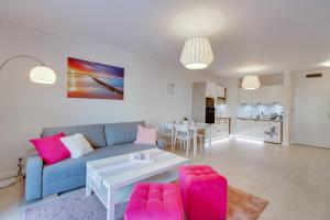 尤斯托尼莫斯基Apartament Crystal的客厅配有蓝色的沙发和粉红色的椅子