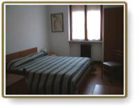努斯杜亚尼酒店的一间卧室设有一张床、一个窗口和一把椅子
