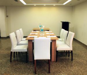 新德里象牙白32酒店的一间会议室,配有木桌和白色椅子