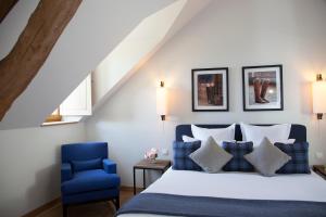 Surville叙尔维尔庄园的一间卧室配有一张床和一张蓝色椅子