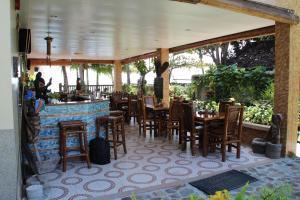 Zamboanguita威尔海滩潜水度假酒店的一间带桌椅的餐厅和一间酒吧