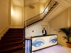 马德里马德里阿克塞尔酒店 - 仅限成人的站在楼梯旁,墙上画着眼睛的人