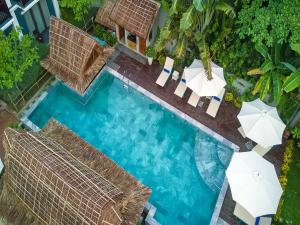 会安AIRA Boutique Hoi An Hotel & Villa的享有带遮阳伞的游泳池的顶部景致