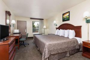 奥古斯塔Heritage Inn Augusta的酒店客房配有一张床、一张书桌和一台电视。