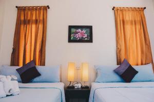 Damnoen Saduak班兰可龙度假村的一间卧室配有两张床和橙色窗帘