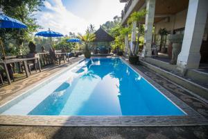 乌布Villa Kalisat Resort的一个带桌子和遮阳伞的大型蓝色游泳池