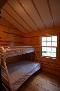 Lyndon StationYukon Trails Camping Resort的小木屋内的双层床,设有窗户