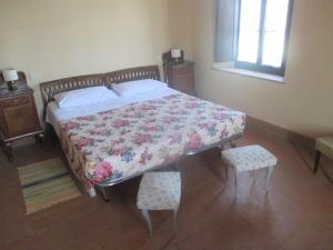萨尔泰阿诺Agriturismo Stigliano的一间卧室配有一张带花卉床罩的床和两把椅子