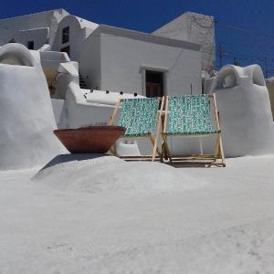 皮尔戈斯奥丽雅传统洞穴度假屋的房子前面的沙子里有两把椅子