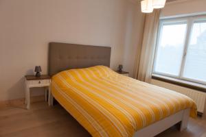 东代恩凯尔克De Witte Parel的一间卧室配有一张带黄条纹毯子的床