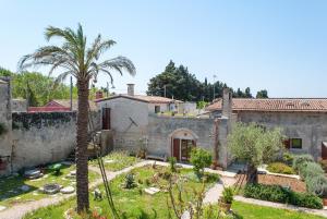 米内尔维诺迪莱切B&B Masseria Dei 12 Granai的院子里有棕榈树的房子