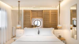 阿吉奥斯普罗科皮奥斯18 Grapes Hotel的卧室配有白色的床和镜子