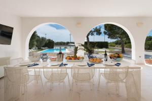 莱乌卡Villa Maria Clara by Perle di Puglia的一间带桌椅的用餐室和一个游泳池