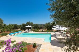 奥斯图尼Villa Sogno Bianco by BarbarHouse的一个带遮阳伞和紫色鲜花的游泳池