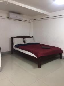 曼谷阿尔萨娜酒店的一间卧室配有一张床铺,床上铺有红色毯子