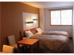 伊豆Hotel Winery Hill的酒店客房设有两张床、一张桌子和一个窗户。