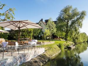 伊亚厄塞尔恩Hotel des Berges, Restaurant Gastronomique & Spa的河边的餐厅,设有桌子和遮阳伞