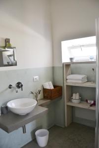 滨海波利尼亚诺Masseria San Martino的浴室设有水槽和带毛巾的架子。