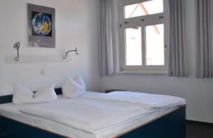 唐格明德Pension Töpferhof的一间卧室配有一张带白色床单的床和一扇窗户。