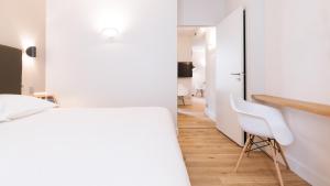 波尔多Appartement T4 Le Courbin的卧室设有白色墙壁、书桌和白色椅子。