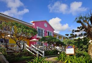 垦丁大街垦丁夏都沙滩酒店的粉红色和黄色的建筑,前面有标志