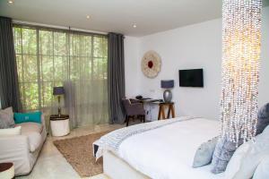 卢萨卡纬度15度酒店的卧室配有一张白色的大床和一张沙发。