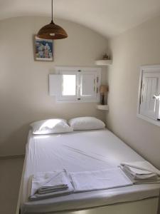Éxo GoniáCosy studio in Santorini的一间卧室配有一张带白色床单的床和一扇窗户。