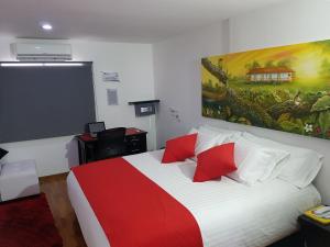 亚美尼亚圣赫罗尼莫亚美尼亚酒店的卧室配有红色和白色的床,墙上挂有绘画作品