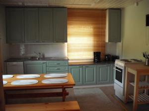 LemmenjokiAhkula House的厨房配有绿色橱柜和带垫子的木桌