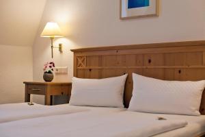 瓦尔多夫格鲁恩斯霍夫酒店的一间卧室配有两张带白色枕头和桌子的床。