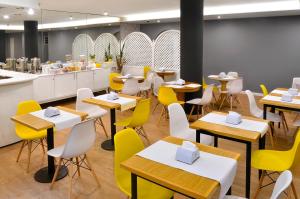 蒙得维的亚希斯潘诺酒店的用餐室配有桌子和黄色椅子