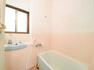 嬬恋村书林酒店的粉红色的浴室设有浴缸和水槽