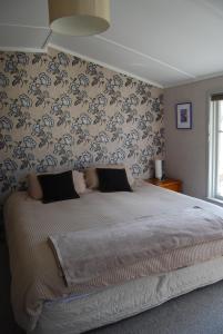 亚历山德拉Judge Rock Exclusive Vineyard Cottage Accommodation度假屋的一间卧室配有一张带花卉壁纸的大床