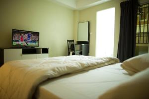 Bang Kew Yai素万那普公寓式酒店的卧室配有白色的床和电视。