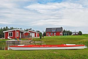 PaežeriaiVilla Ievynė的坐在房子前面的草上的一个红船