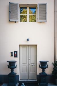 帕尔马Palazzo Gozzi Bed & Beauty的门前有两瓶花的白色房子