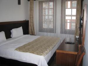 阿马西亚西马酒店的一间卧室配有一张床、一张书桌和两个窗户。