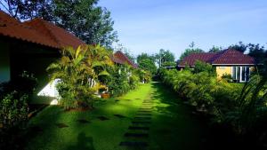 蔻立查普特拷叻度假屋的绿色庭院,有房子和棕榈树