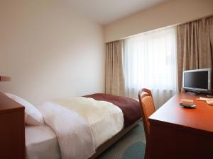 盛冈盛冈珍珠城市饭店的酒店客房配有一张床和一张书桌及一台电视