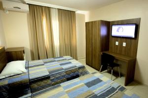 若阿萨巴Hotel do Comércio的配有一张床和一台平面电视的酒店客房