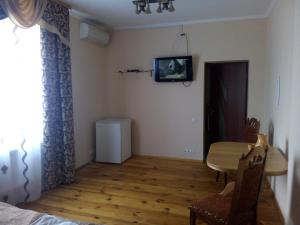 YahotynOselya Guest House的一间设有桌子和墙上电视的房间