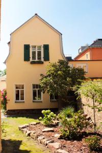 拉德博伊尔Ferienhaus Mühlberg的黄色的房屋,设有绿色百叶窗和花园