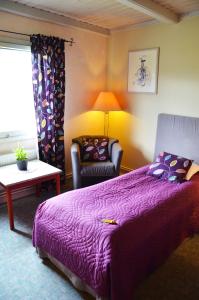 BräckeJämtkrogen Hotell的一间卧室配有一张紫色的床和一把椅子