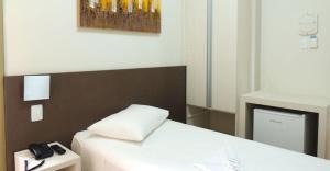 迪维诺波利斯Excellence Comfort Hotel的一间房间,配有一张床和电话