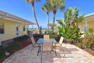 威尼斯凯西基海滩公寓式酒店的一个带玻璃桌和椅子的庭院,并种植了棕榈树