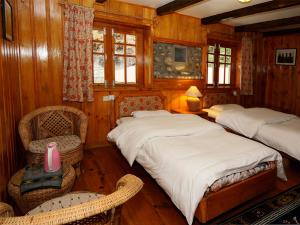 PhakdingMountain Lodges of Nepal - Phakding的一间卧室设有两张床、一把椅子和窗户。