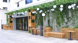 上海康铂酒店(上海火车站人民广场店)的商店前方设有木凳和绿色的墙壁